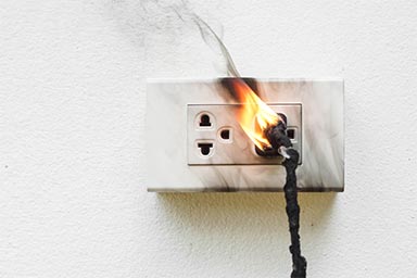 electrical outlet with a plug plugged in but also on fire