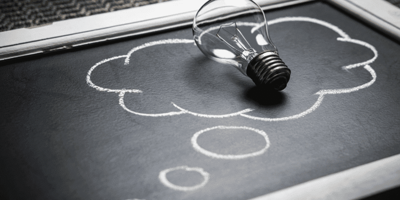 lightbulb lying on a chalkboard with a thought bubble drawn under it invoking the visual of an idea