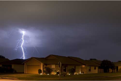 lightning striking in the distance behind a house