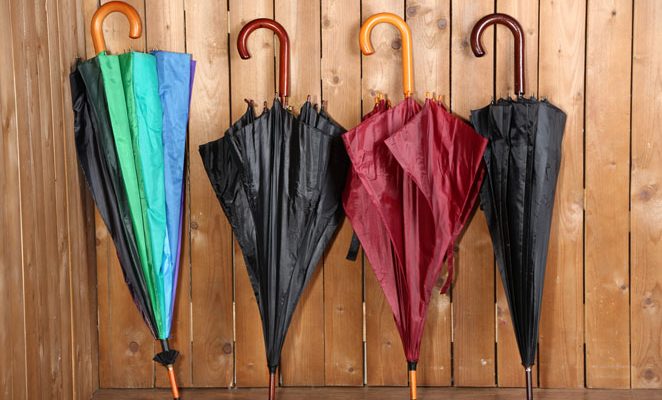 Four closed umbrellas leaning against a wooden wall